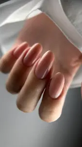 Glanzende nude amandelvormige nagels tegen witte zijde