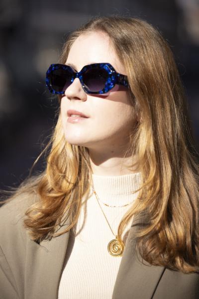 Vrouw draagt een blauwe zonnebril met patroon in het zonlicht