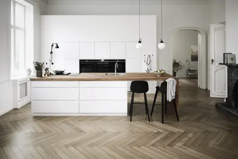 MANO witte keuken met strakke kasten, minimalistisch design en houten werkbladen, die Scandinavische elegantie combineert met functionele moderniteit.