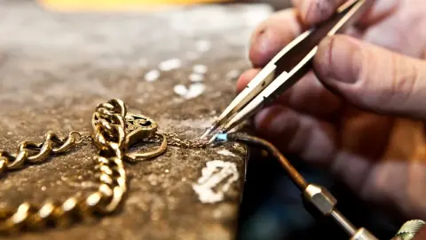 Een gouden ketting wordt met een pincet hersteld