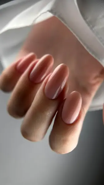 Glanzende nude amandelvormige nagels tegen witte zijde