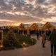 Bezoekers wandelen bij zonsondergang het sfeervol verlichte winterfair-terrein op