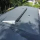 Beeld van een woning met een nieuw gerenoveerd bitumen dak, omringd door een groene tuin