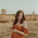 Zwangere vrouw in een warme oranje jurk tijdens een shoot in zacht avondlicht